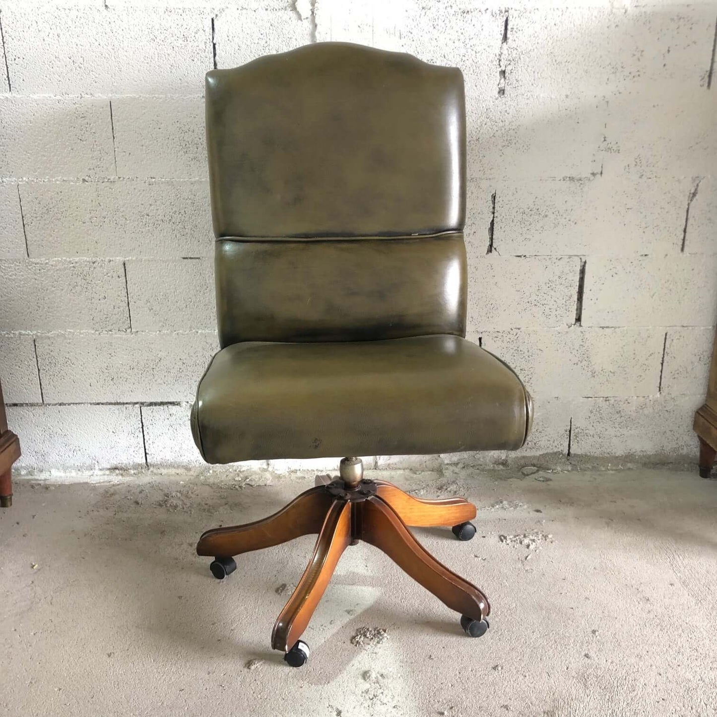 Dark green vintage armchair on wheels in imitation leather